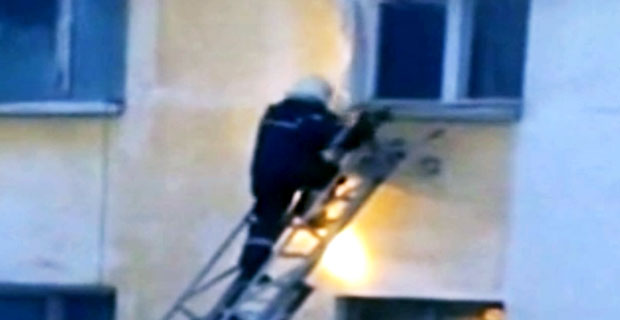 Zalegający śnieg, spada na strażaka idącego po drabinie